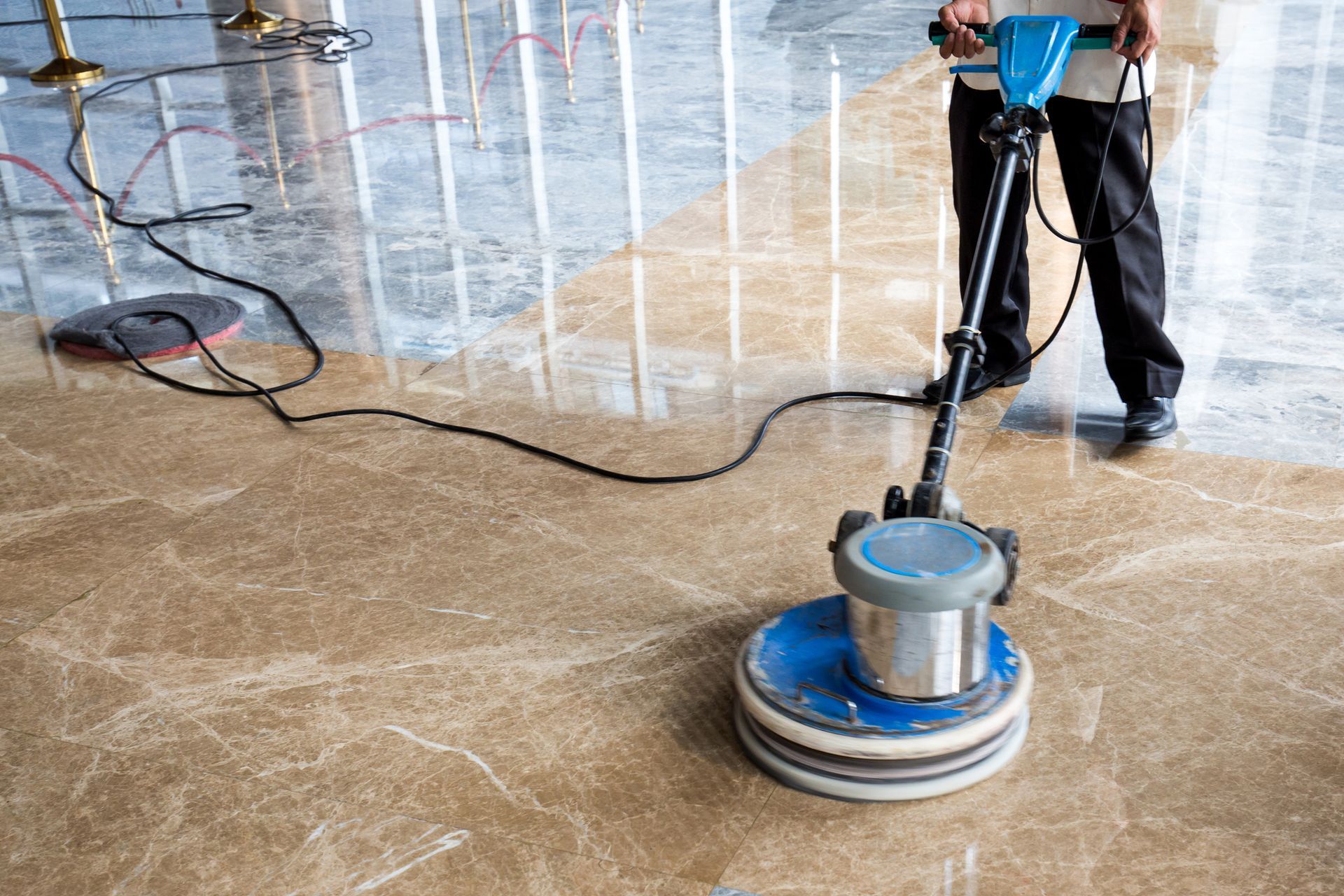 Person using a floor polishing machine on a marble floor.