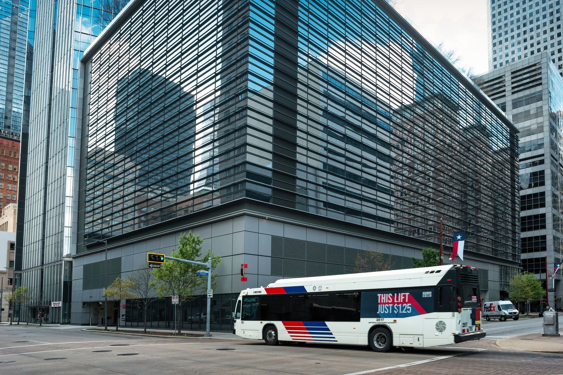 Bus in front of modern glass building. Blue and white bus with logo, street scene.