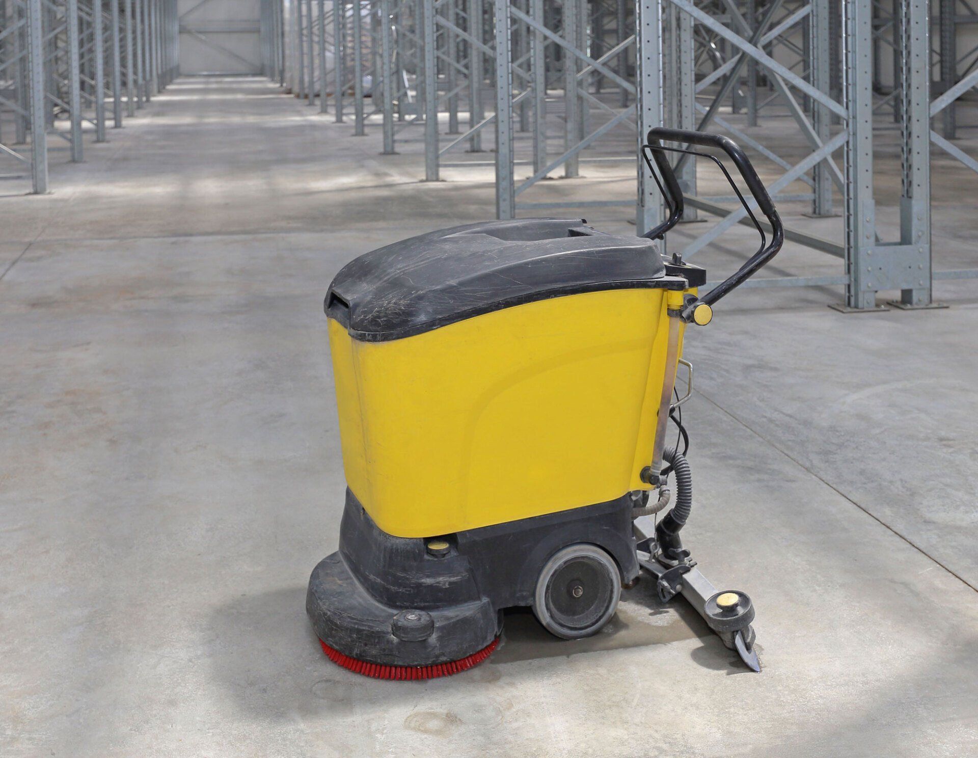 A yellow and black machine is sitting on the floor of a warehouse.