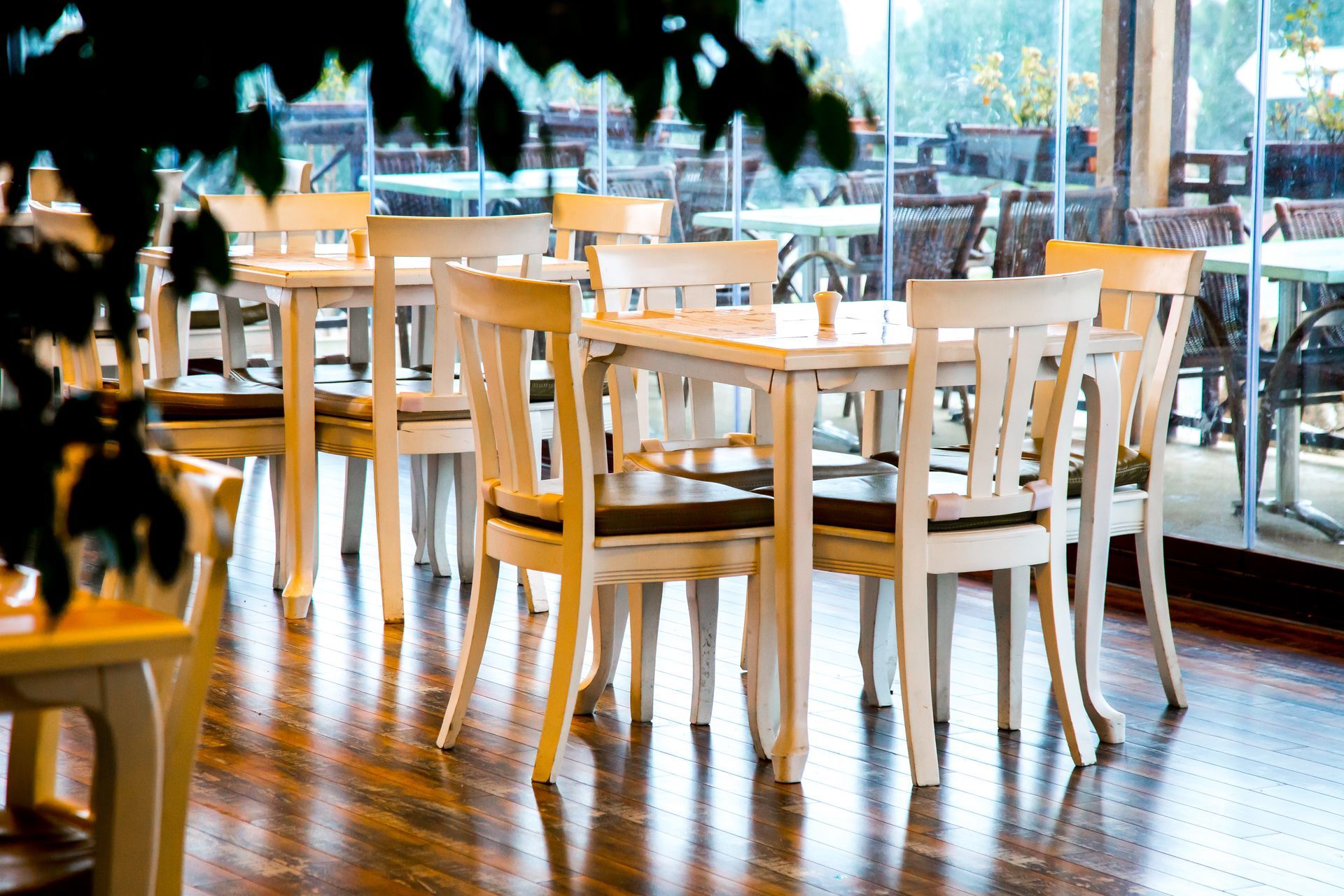 Empty restaurant tables and chairs by a window.