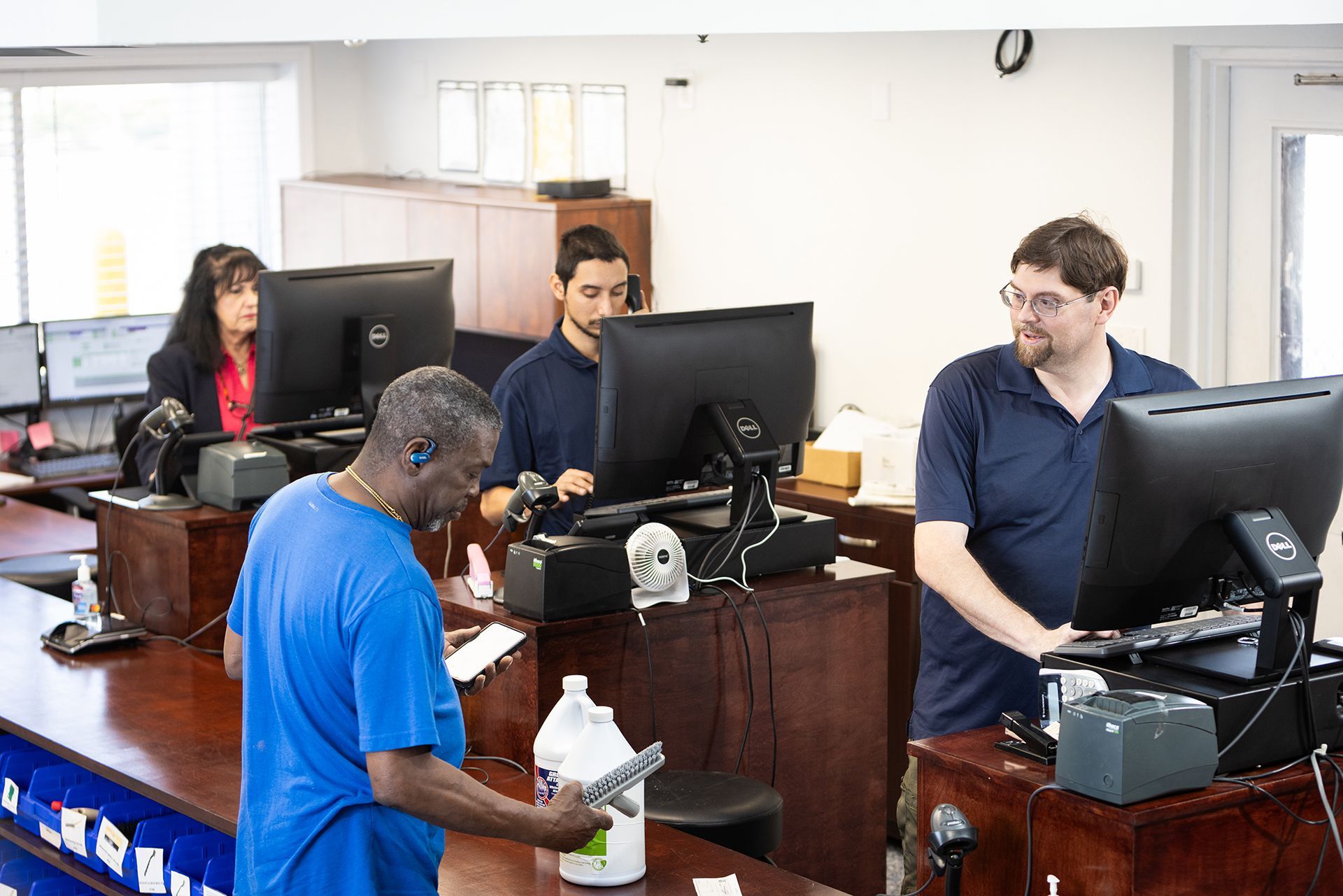 A man in a blue shirt is standing in front of a counter in a store.