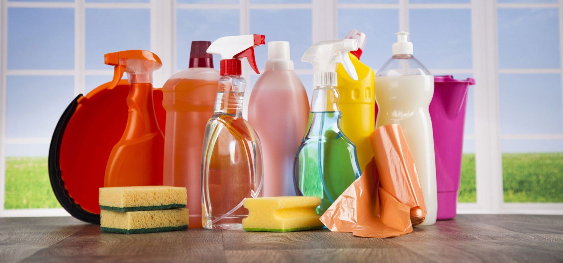 A table topped with bottles of cleaning supplies and sponges.