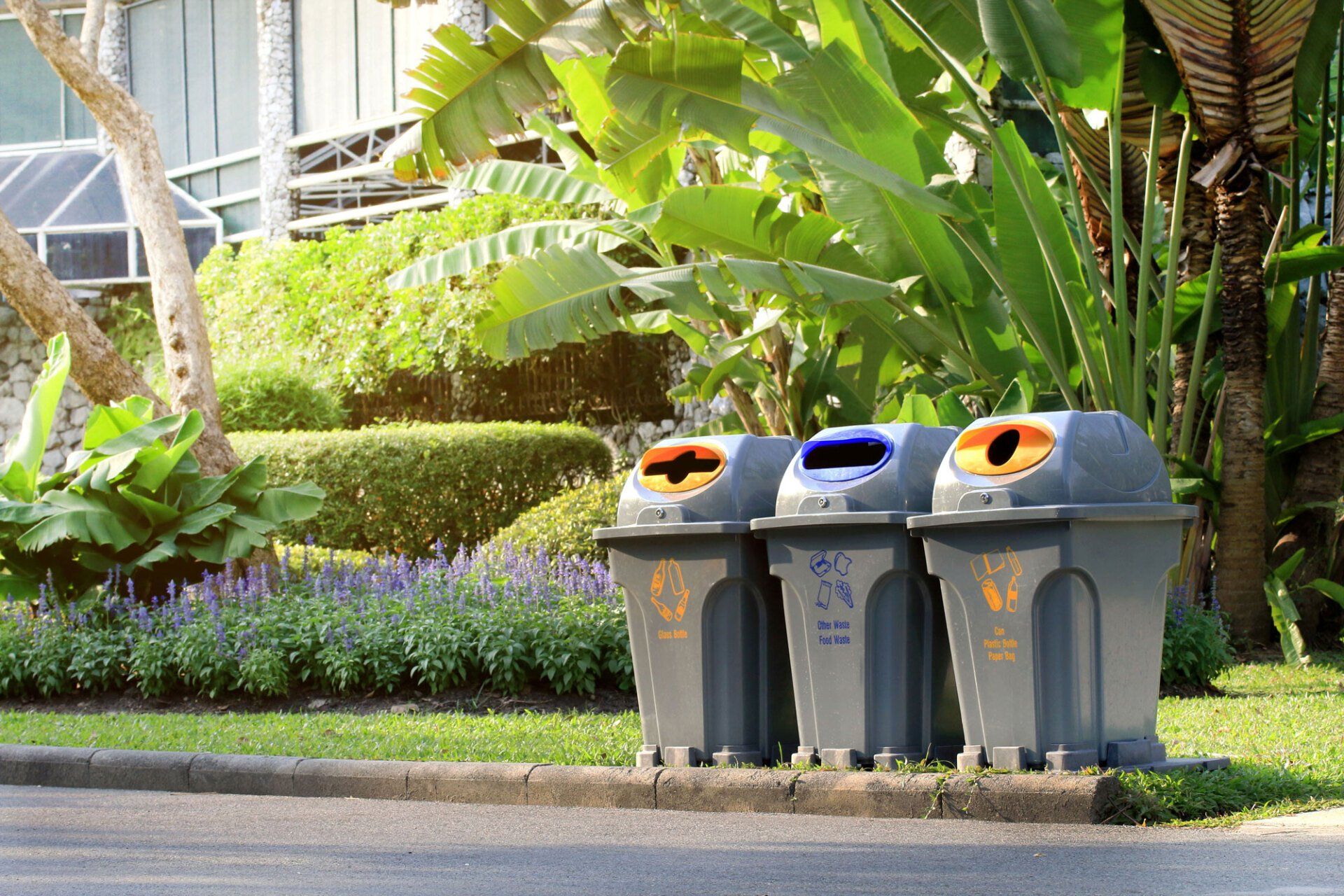 Three trash cans are lined up on the side of the road