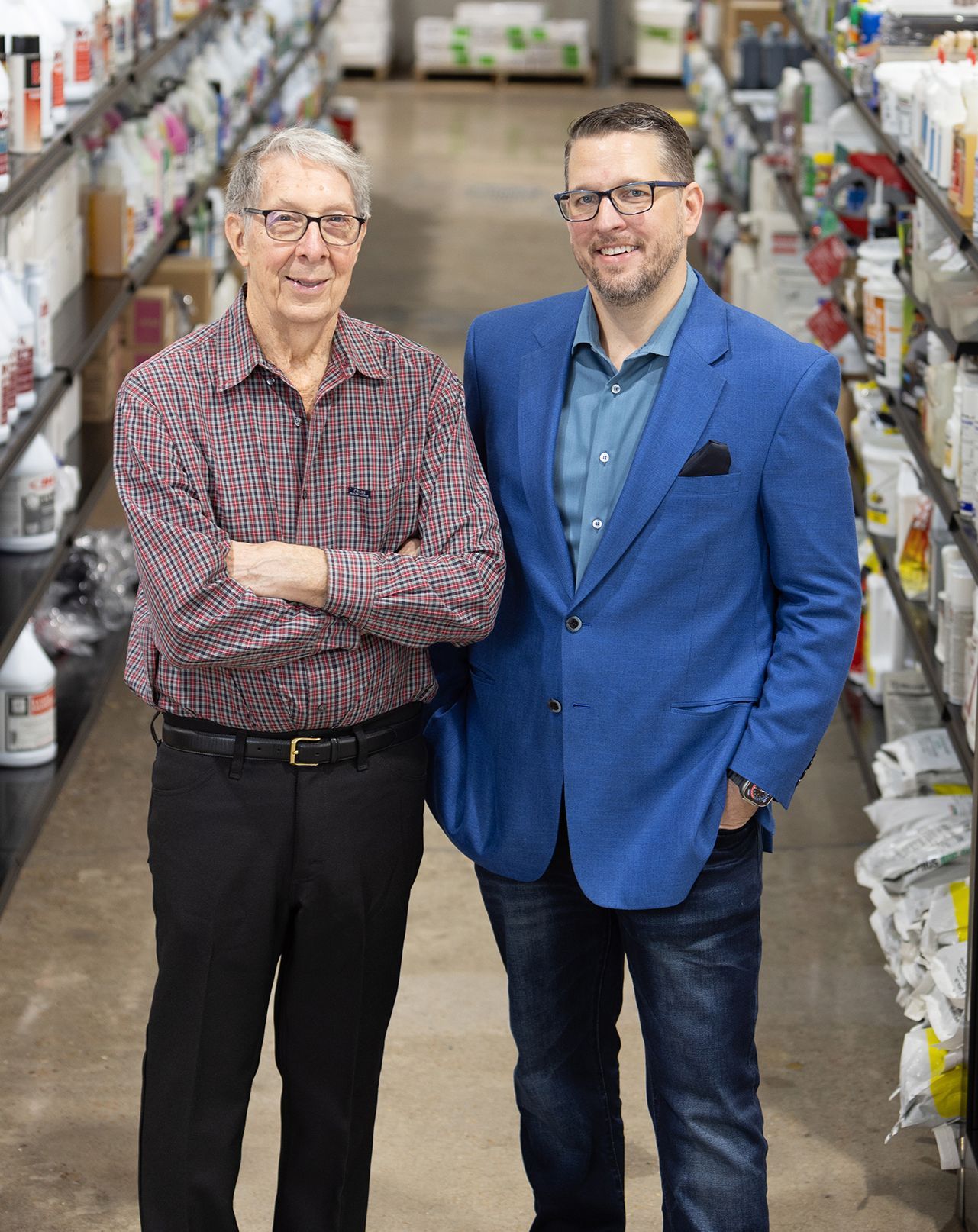 Two men standing in a store aisle, one in a blue blazer and one in a patterned shirt.