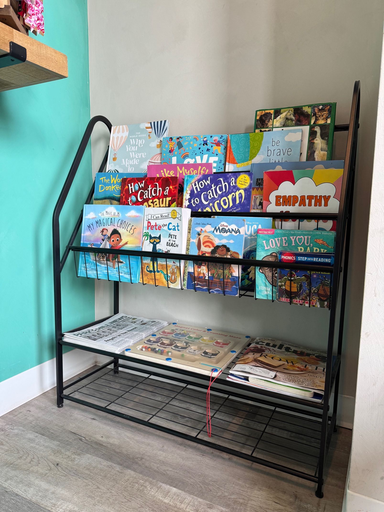 A bookshelf filled with children 's books in a room.