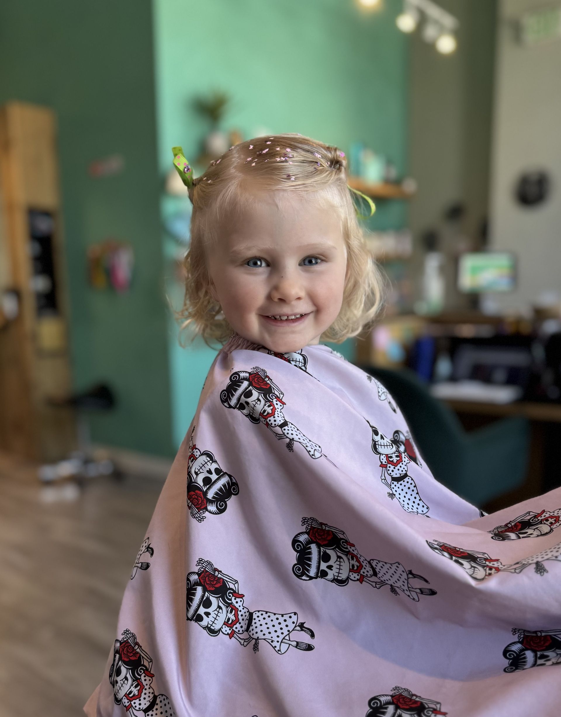 Smiling child wrapped in a pink patterned blanket with a new hair style.