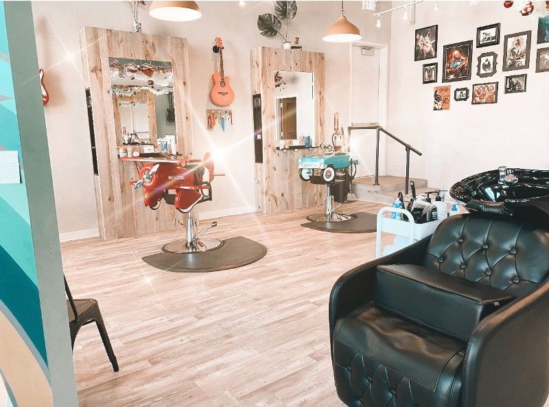 A hair salon with a black chair and a sink.