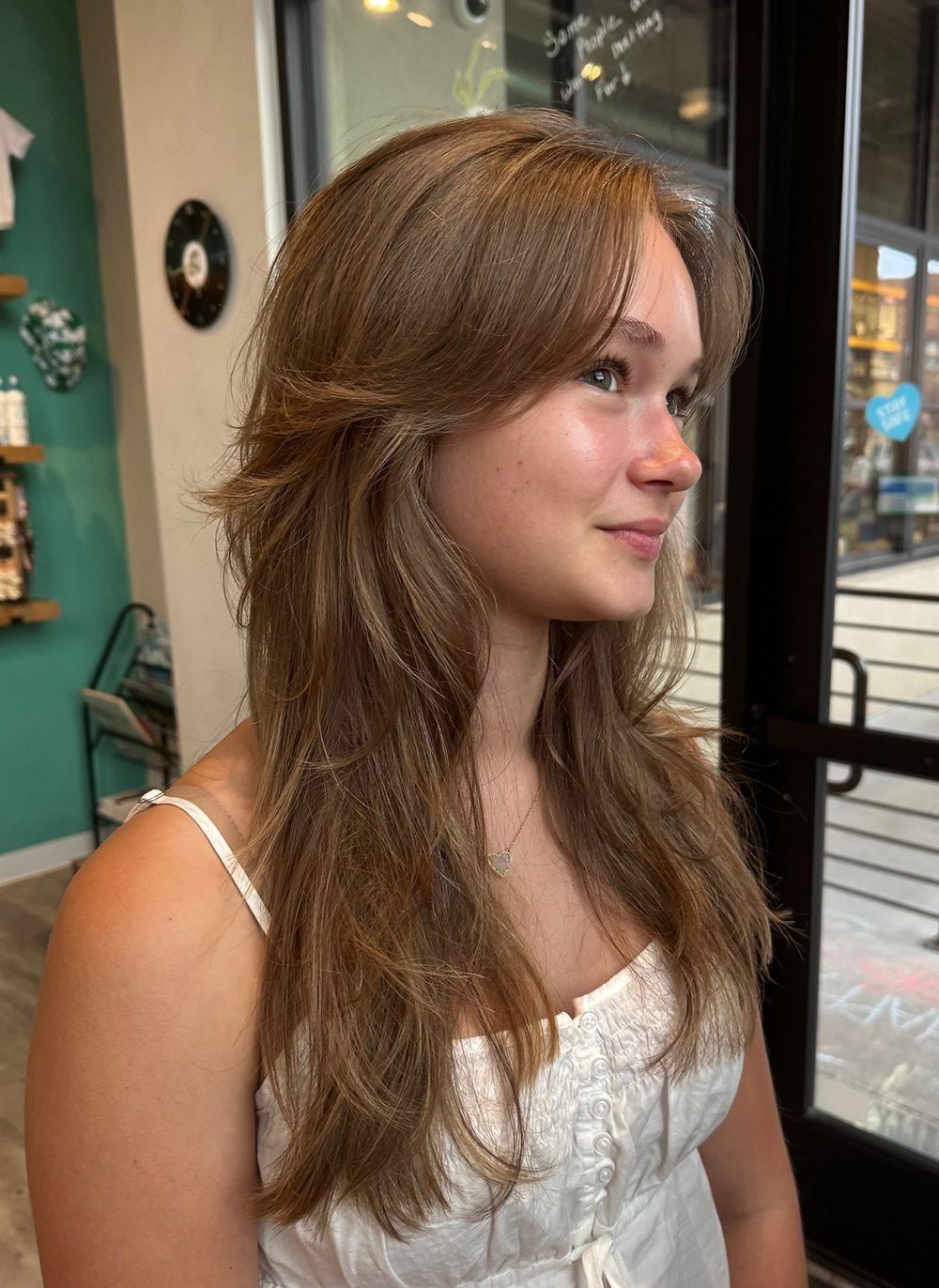 Woman with long, layered brown hair, smiling.
