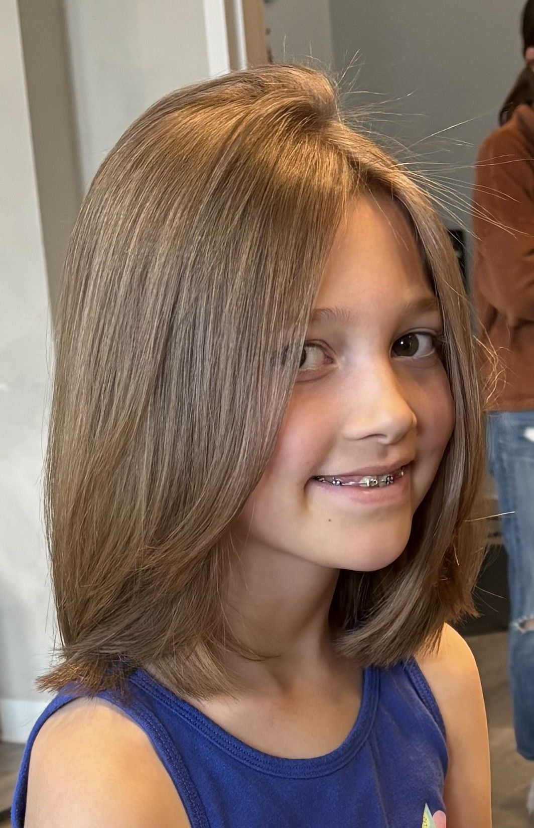 Girl with shoulder-length brown hair, wearing braces, smiling.
