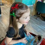 A little girl is sitting in front of a mirror looking at her hair.