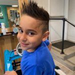 A young boy is getting his hair cut at a barber shop.