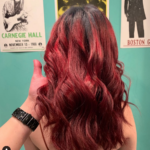 A woman with red hair is standing in front of a wall with posters on it.
