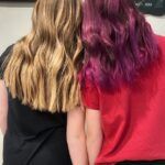 Two girls with purple hair are standing next to each other.