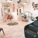 There is a chair in the middle of the room in a hair salon.