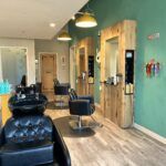 A hair salon with a sink and chairs in it.