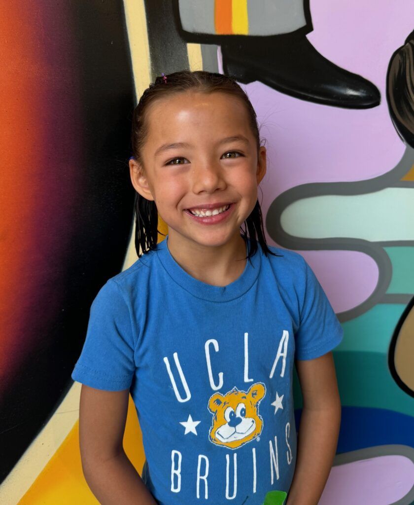 A young girl wearing a blue shirt that says ucla bruins