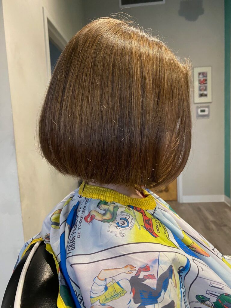 A woman is getting her hair cut in a salon.