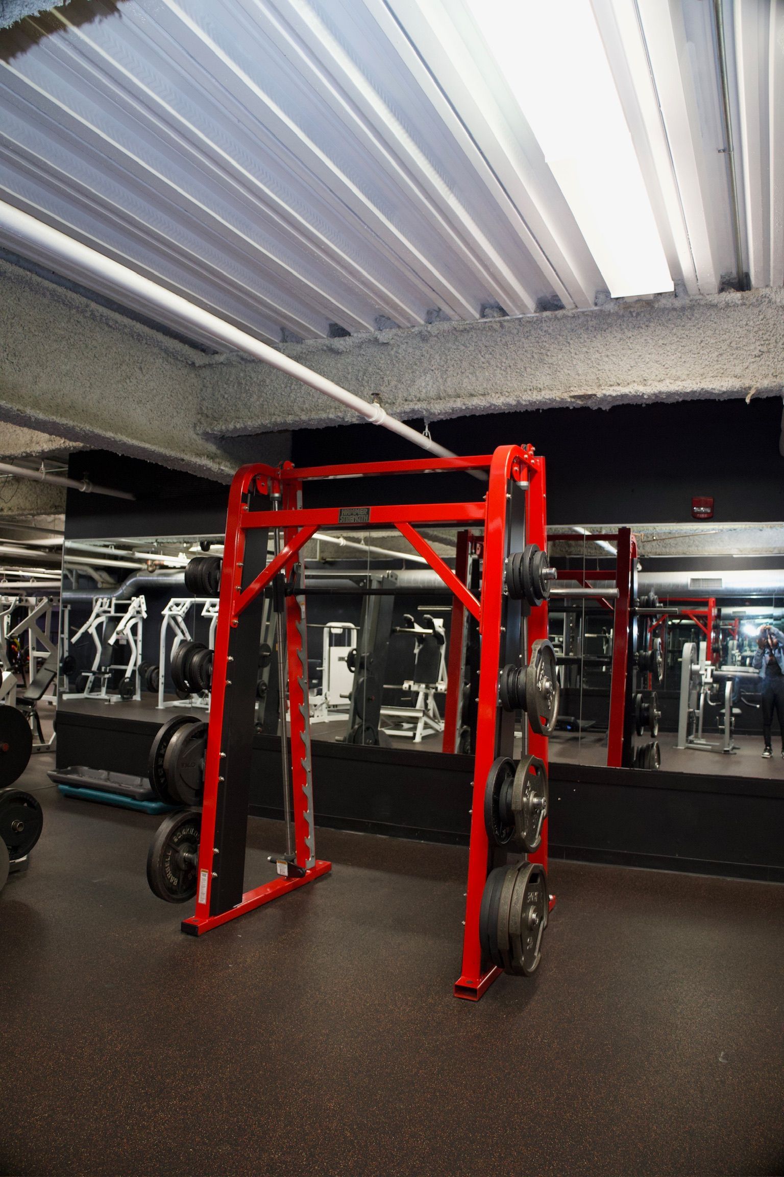 Red weight rack with weights in a gym, with mirrors and other equipment.
