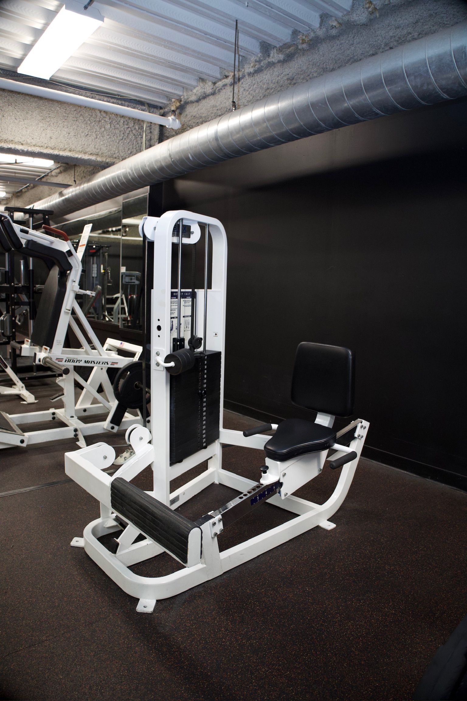 White leg extension machine in a gym setting.