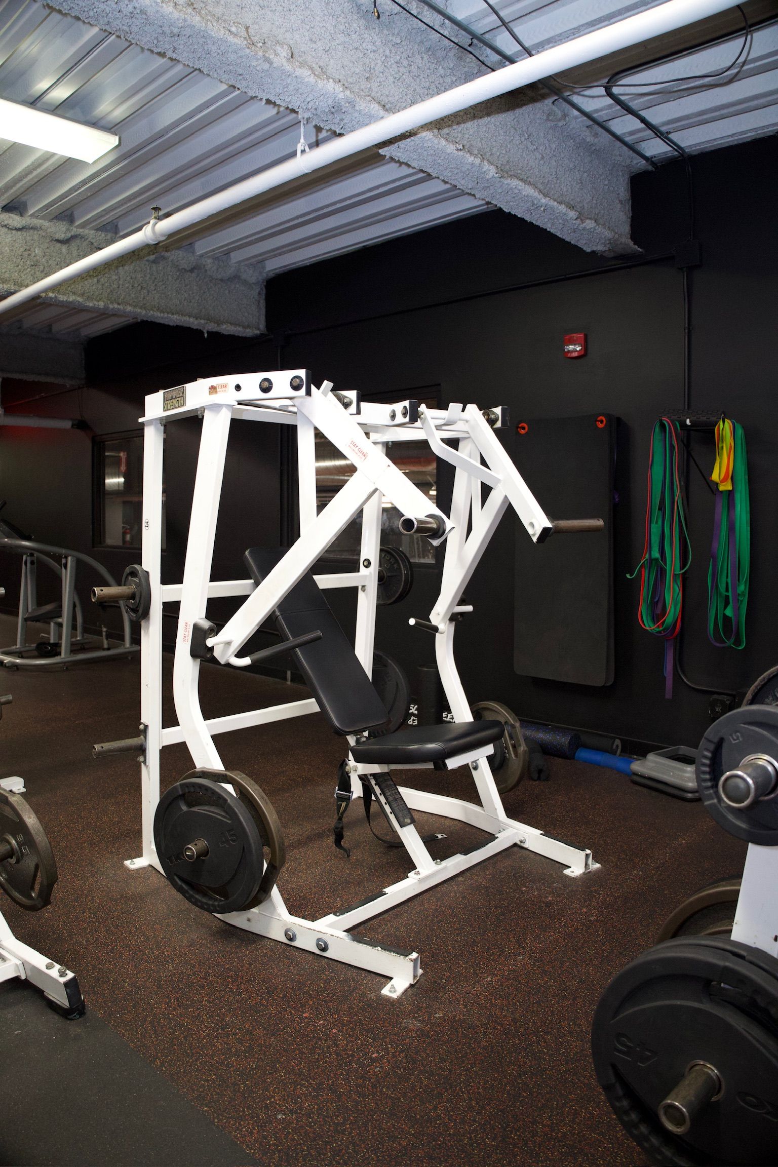 A weight machine in a gym, with weights loaded. Dark room with a rubber floor.