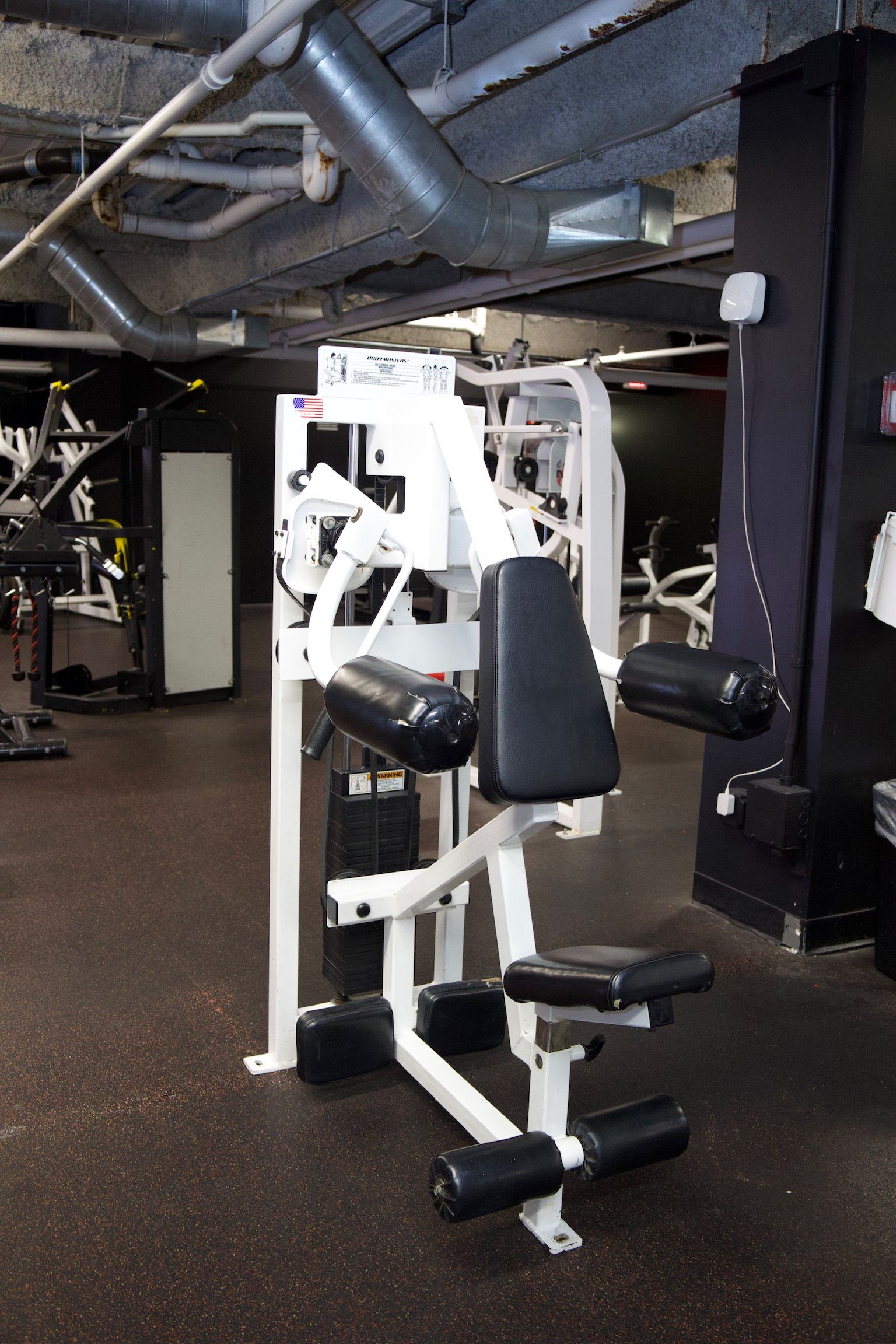 White and black exercise machines in a gym setting.