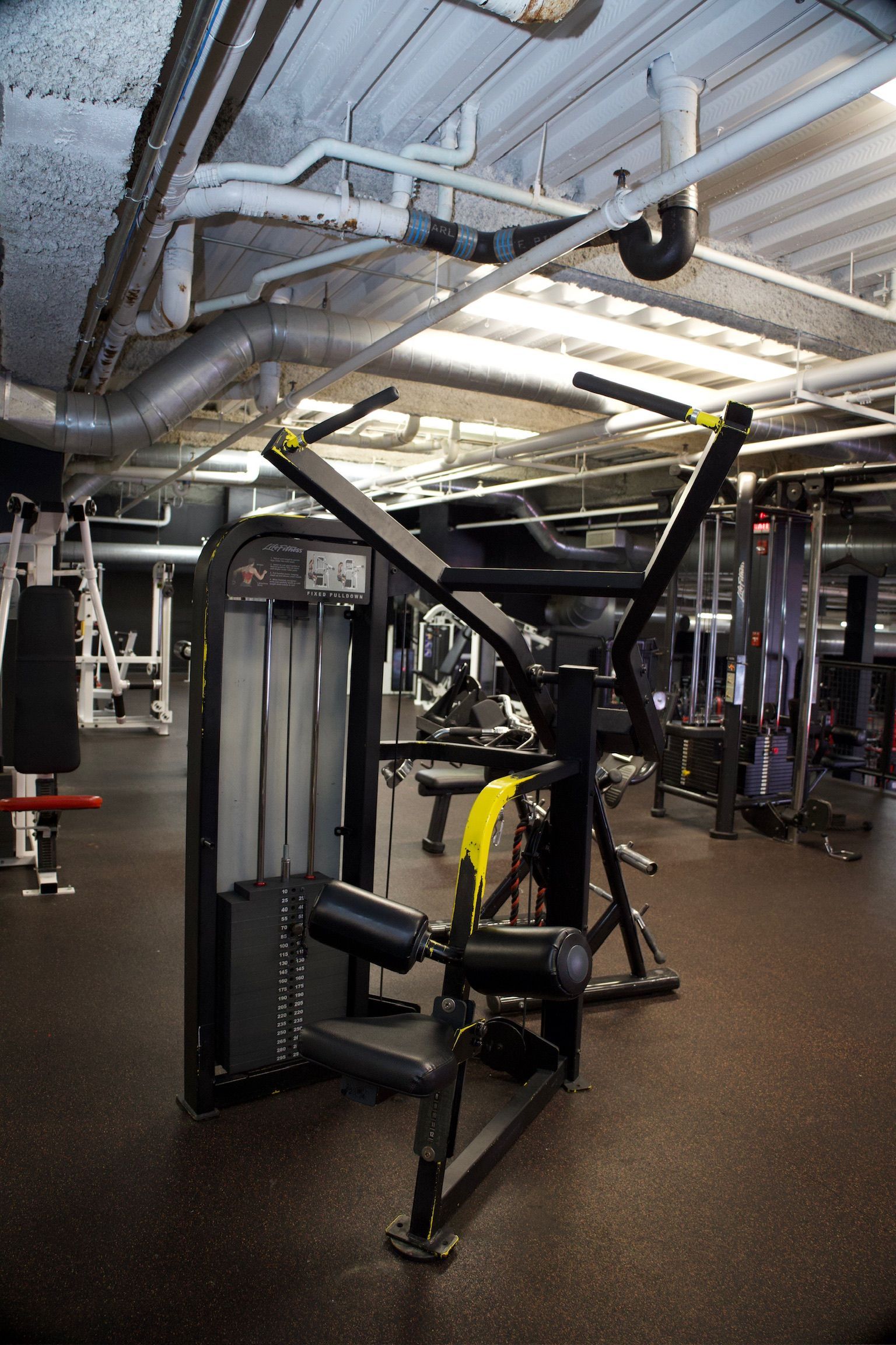 Weight machine in a gym, black and yellow, for upper body workouts.