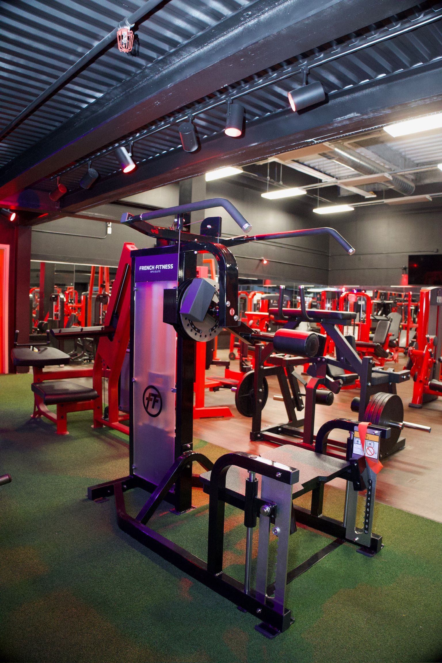 Gym interior with black and red exercise machines on artificial turf.