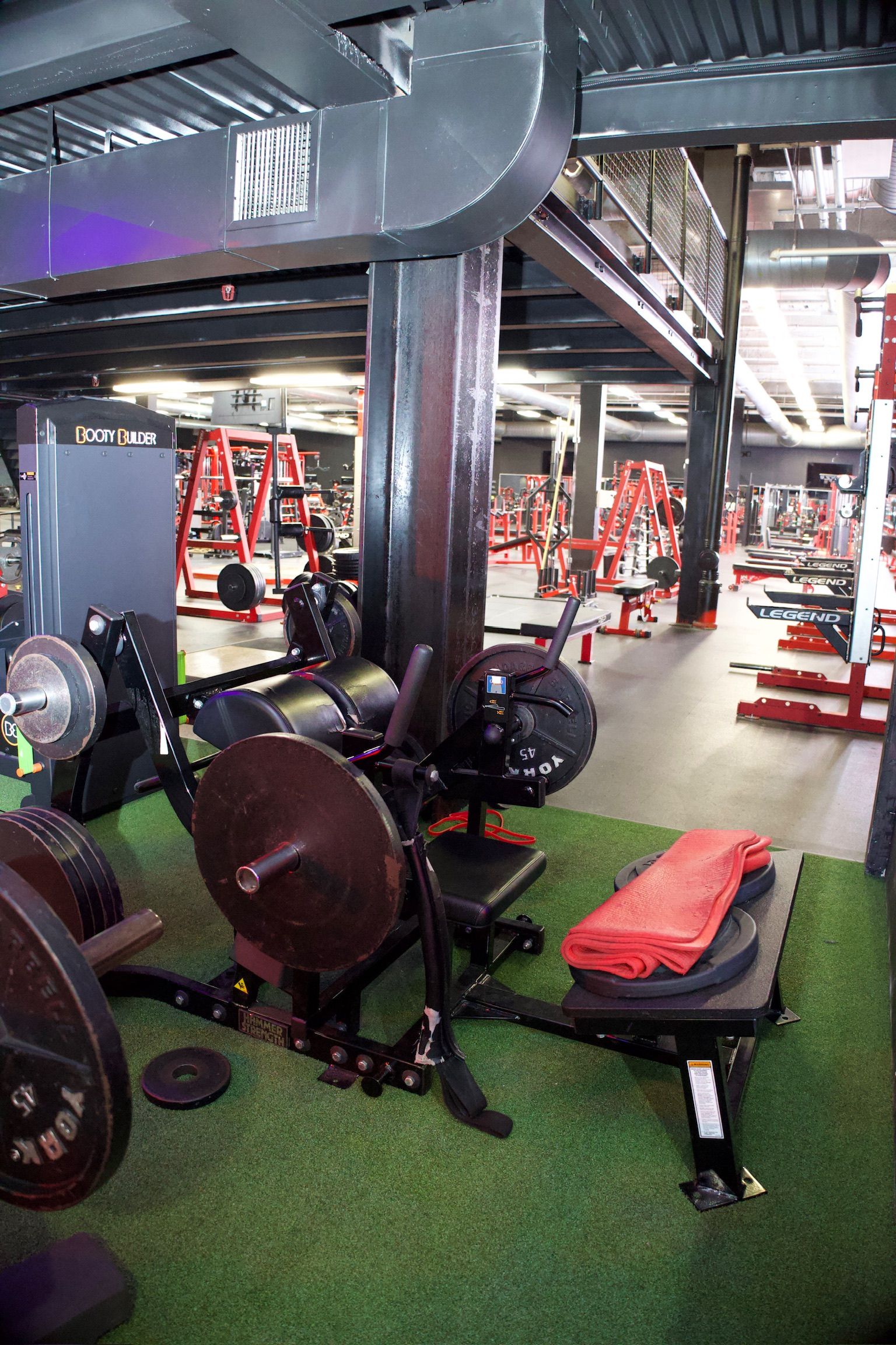 Gym interior with weight machines. Black and red equipment on artificial grass.