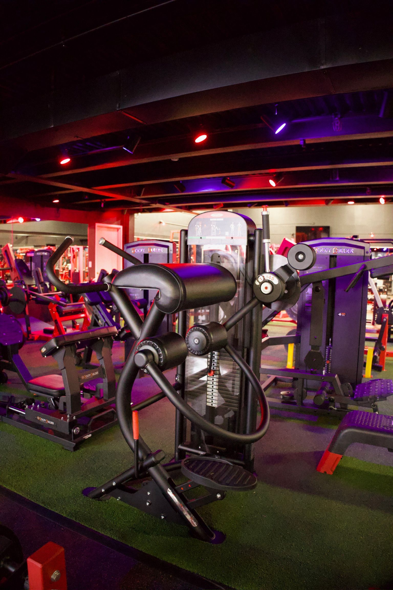 Exercise machine in a gym setting with red and purple lighting.