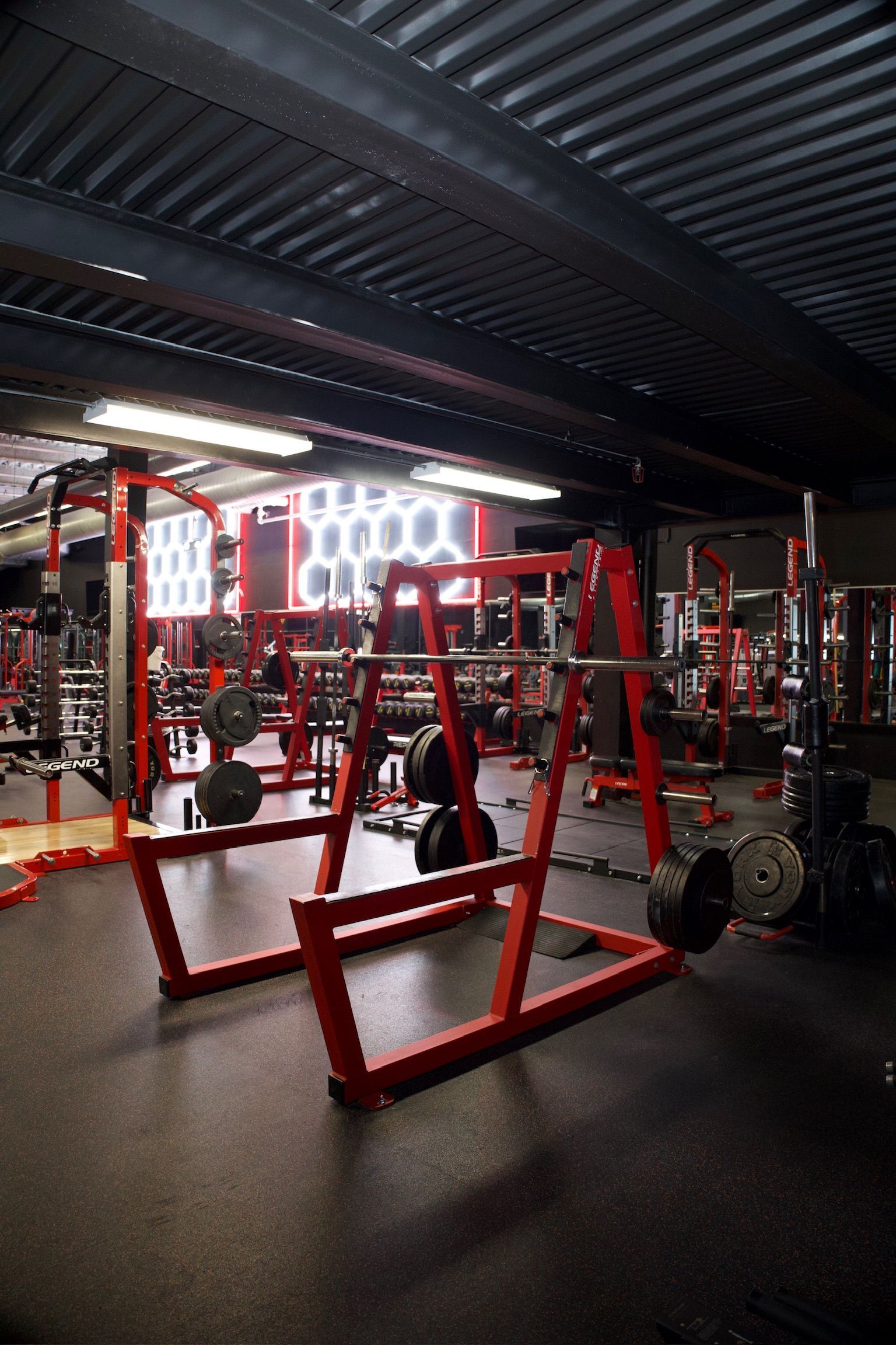 Red weightlifting equipment in a gym, including squat racks, barbells, and weights.