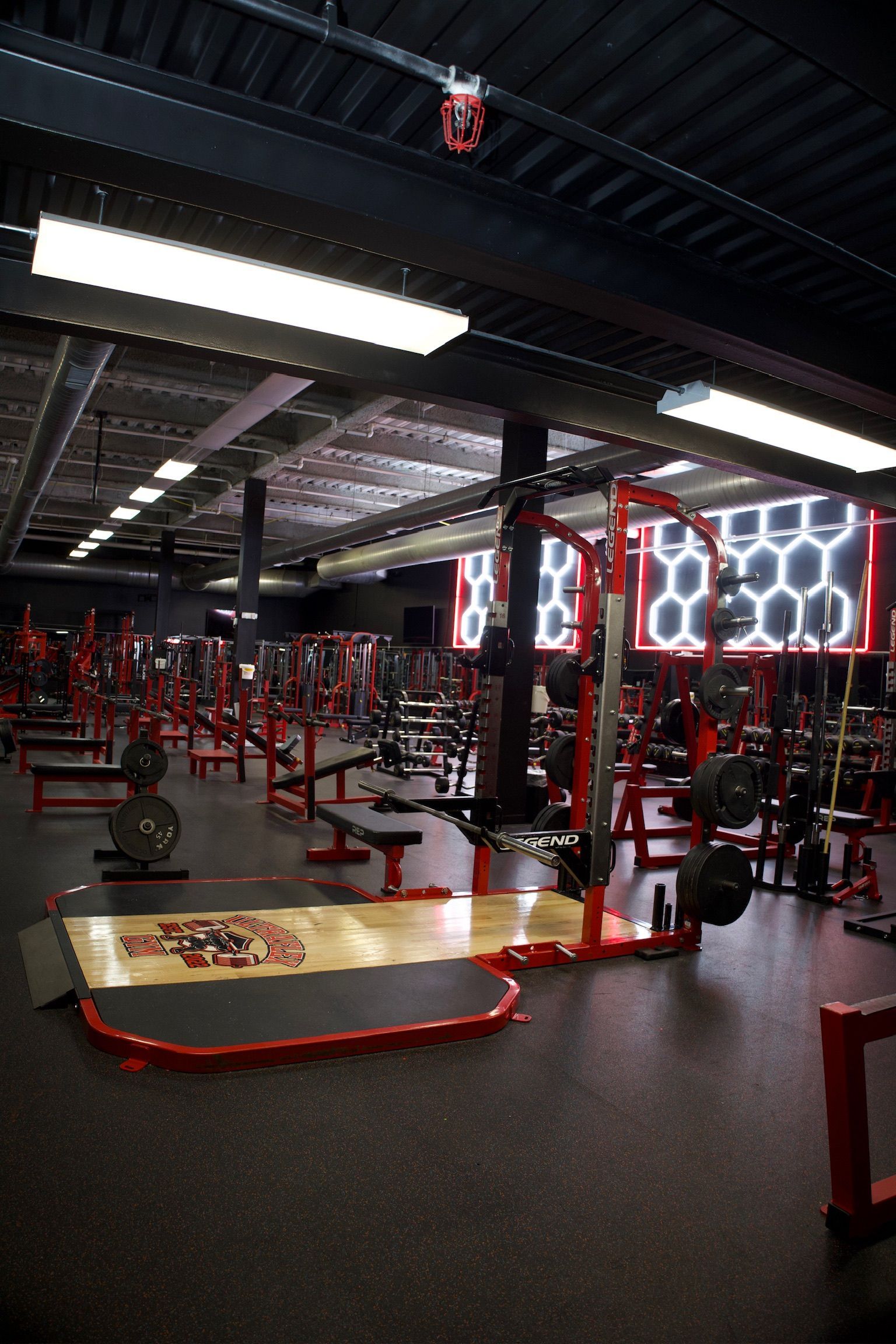 Gym interior with red weightlifting equipment and black flooring.
