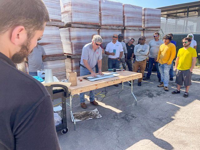 A group of men are standing around a table in a parking lot.