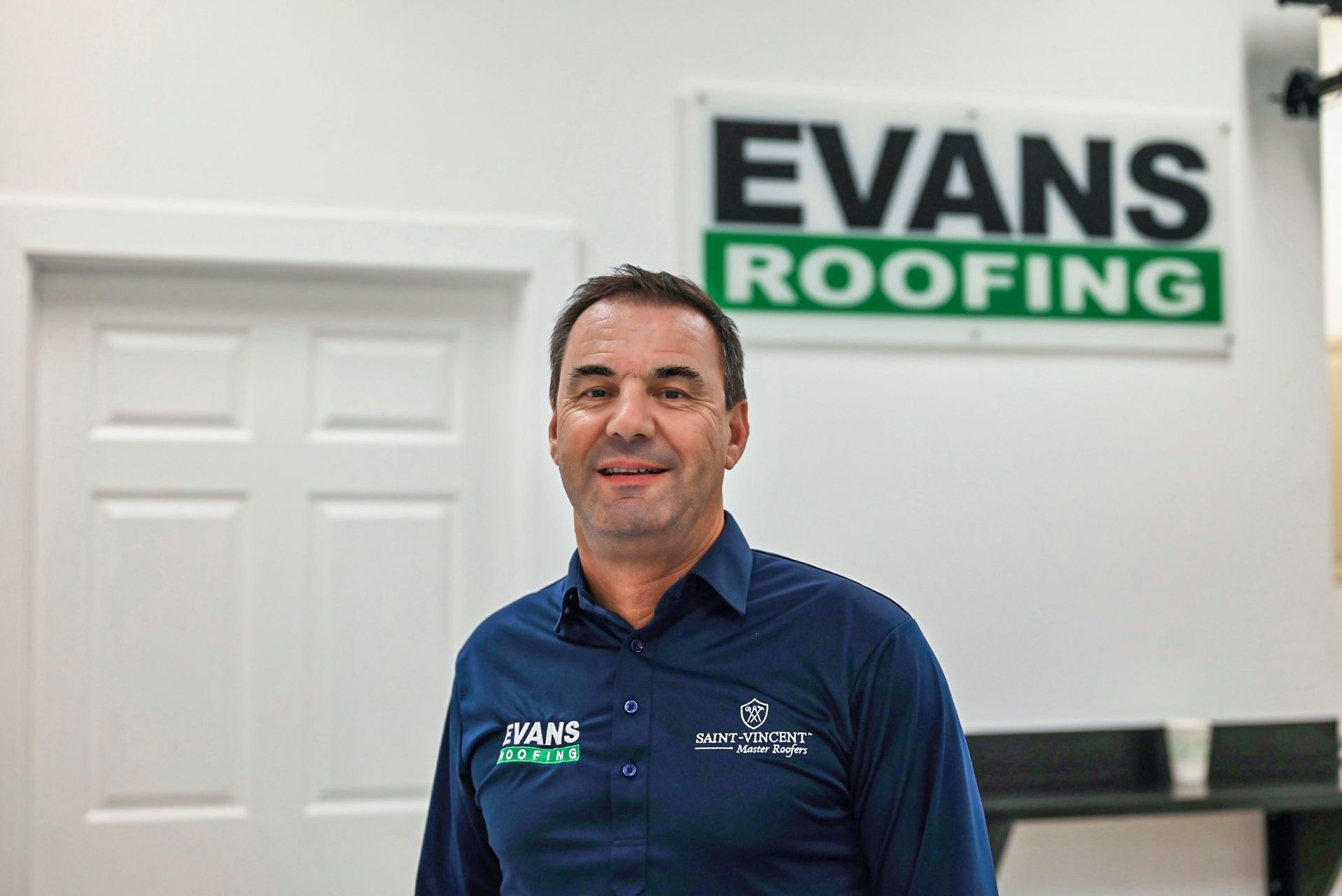 A man is standing in front of a sign that says evans roofing.