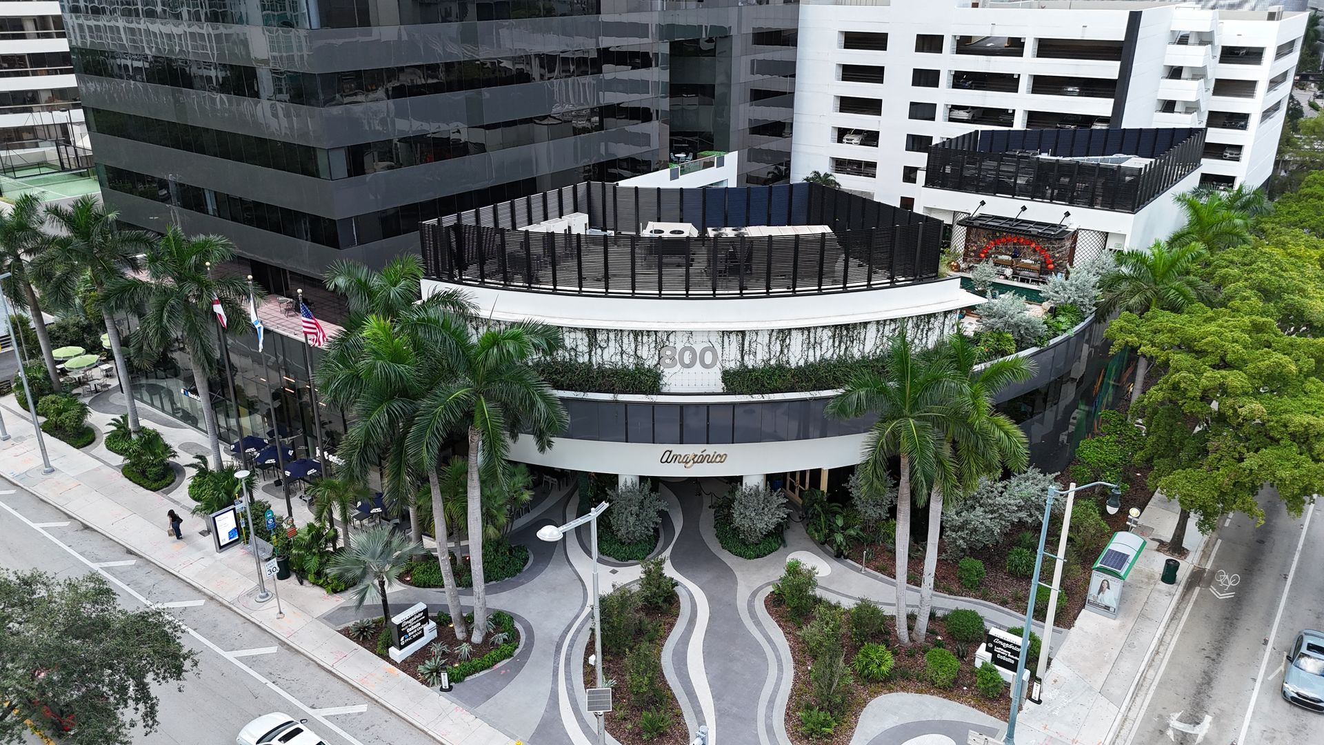 View of a modern building with a rooftop area and palm trees in front.