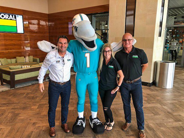 A group of people standing next to a dolphin mascot.