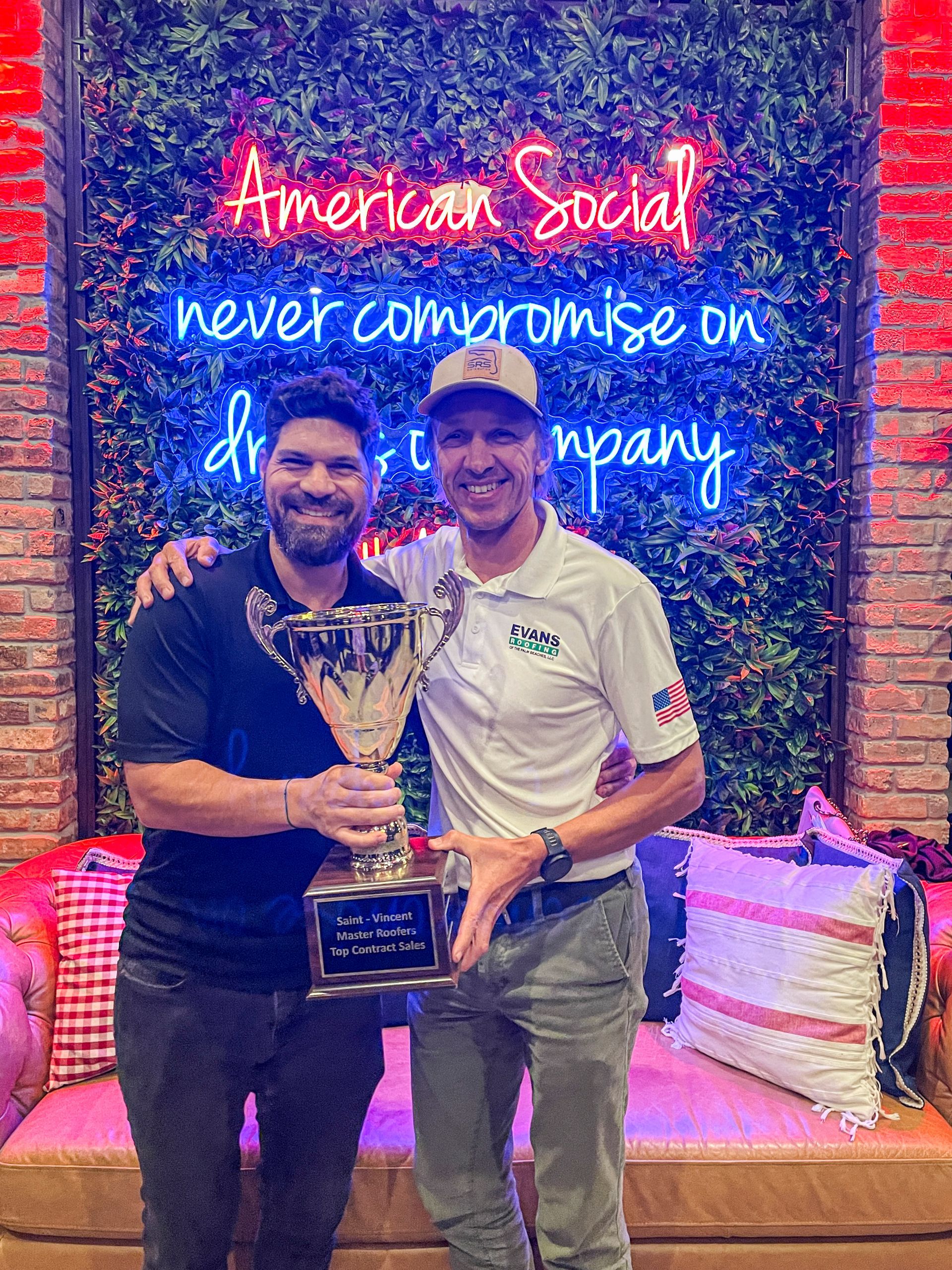 Two men are standing next to each other holding a trophy.