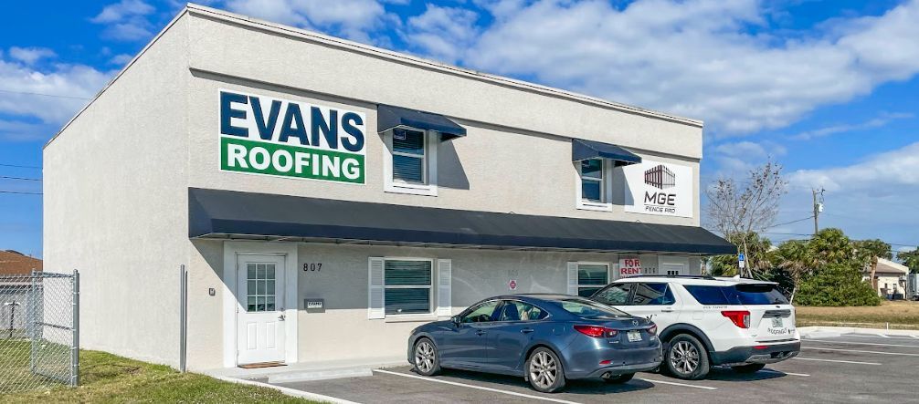 Two cars are parked in front of a building that says Evans Roofing