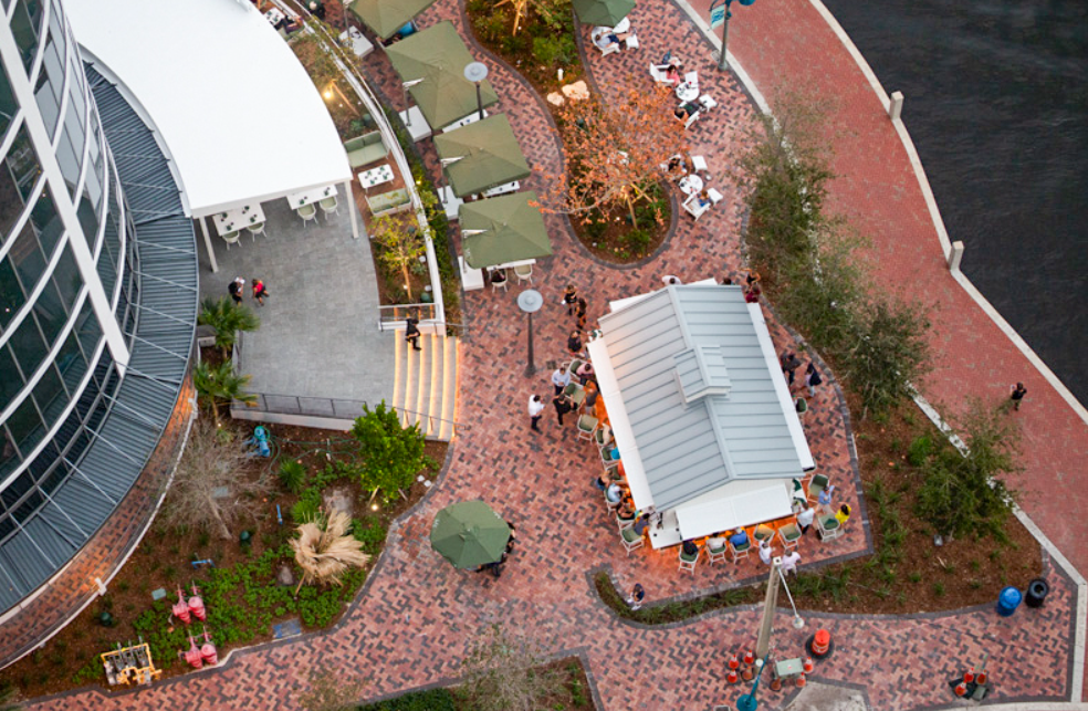 An aerial view of a brick courtyard with people sitting under umbrellas