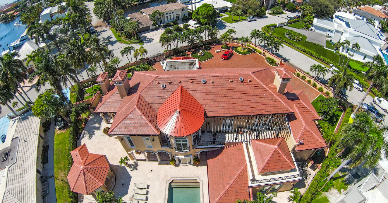 An aerial view of a gated community with palm trees and a pond