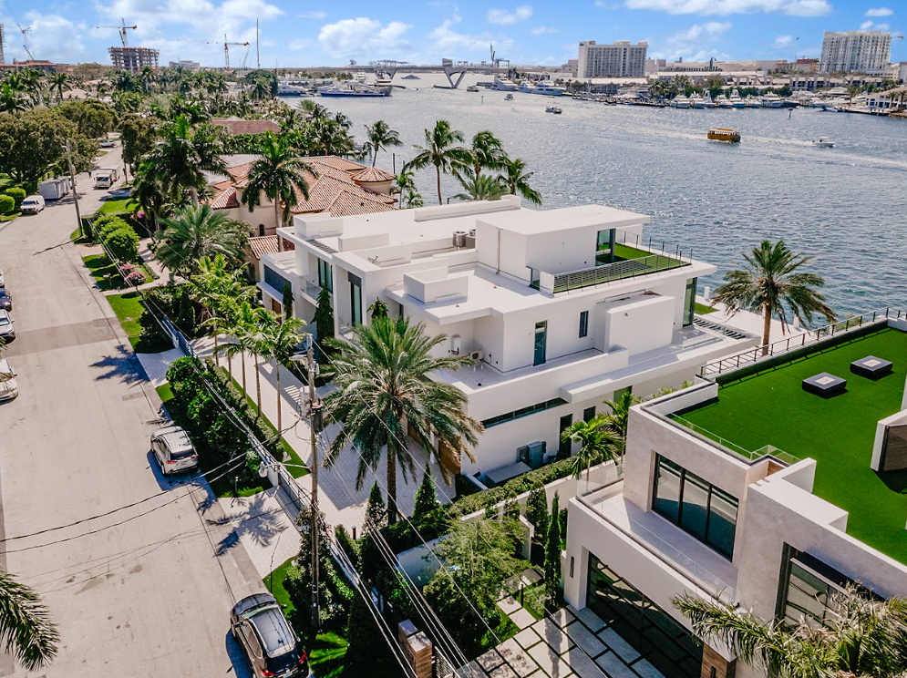 An aerial view of a large white house next to a body of water