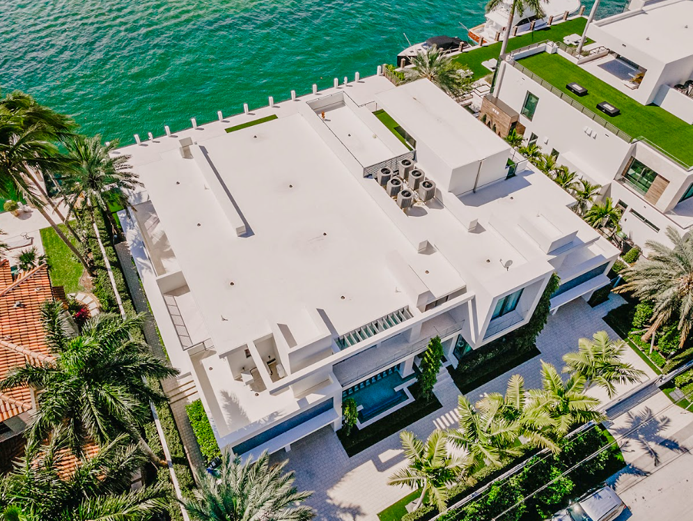 An aerial view of a large white house next to a body of water