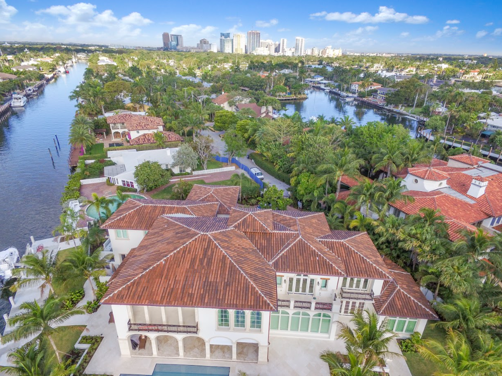 An aerial view of a large house surrounded by trees and a river