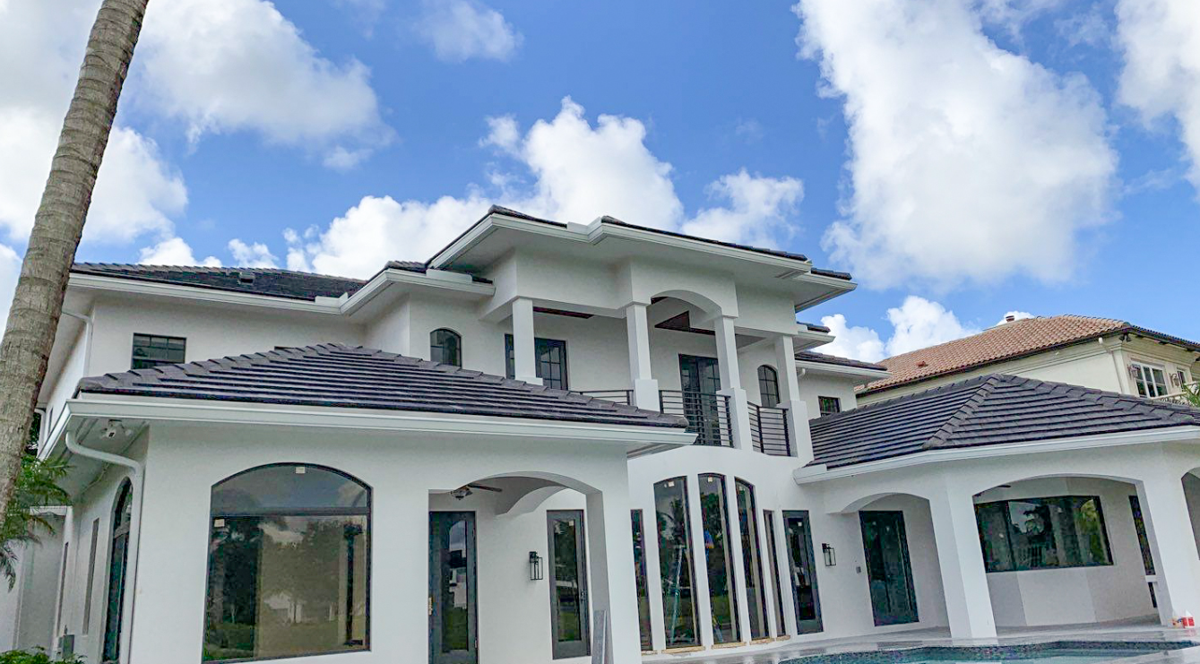 A large white house with a swimming pool and a palm tree in front of it