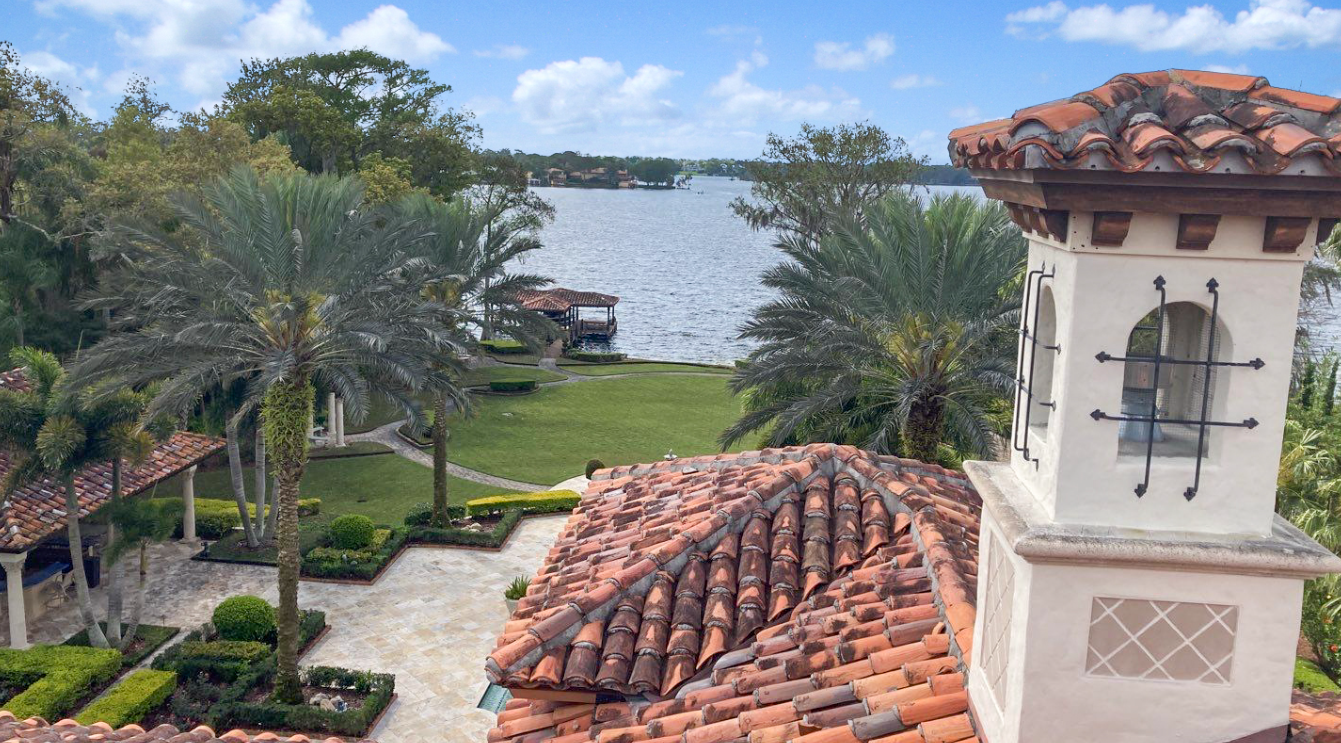 A clock tower on top of a tiled roof overlooking a lake