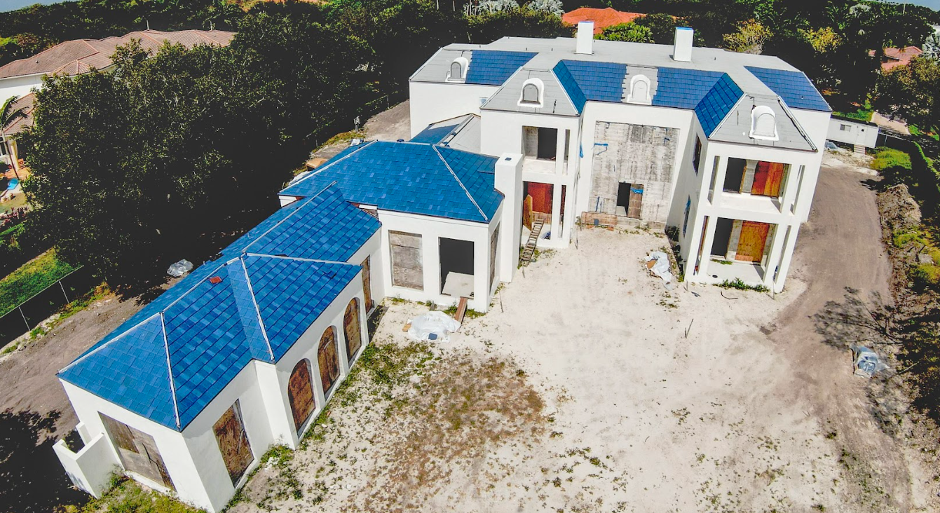 An aerial view of a large house with a blue roof