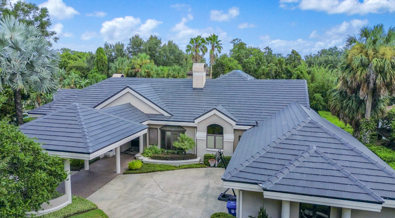 An aerial view of a large house with a blue roof surrounded by trees