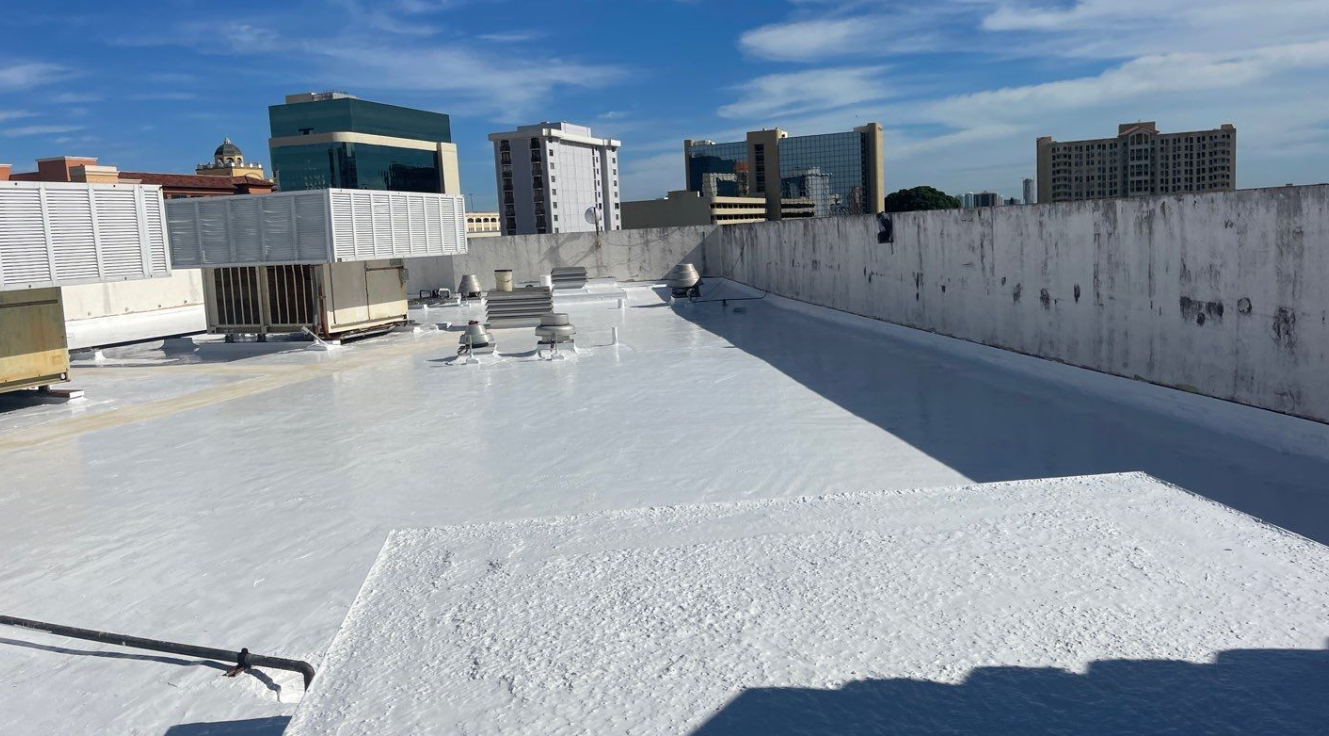 A roof with a lot of white foam on it and a city in the background
