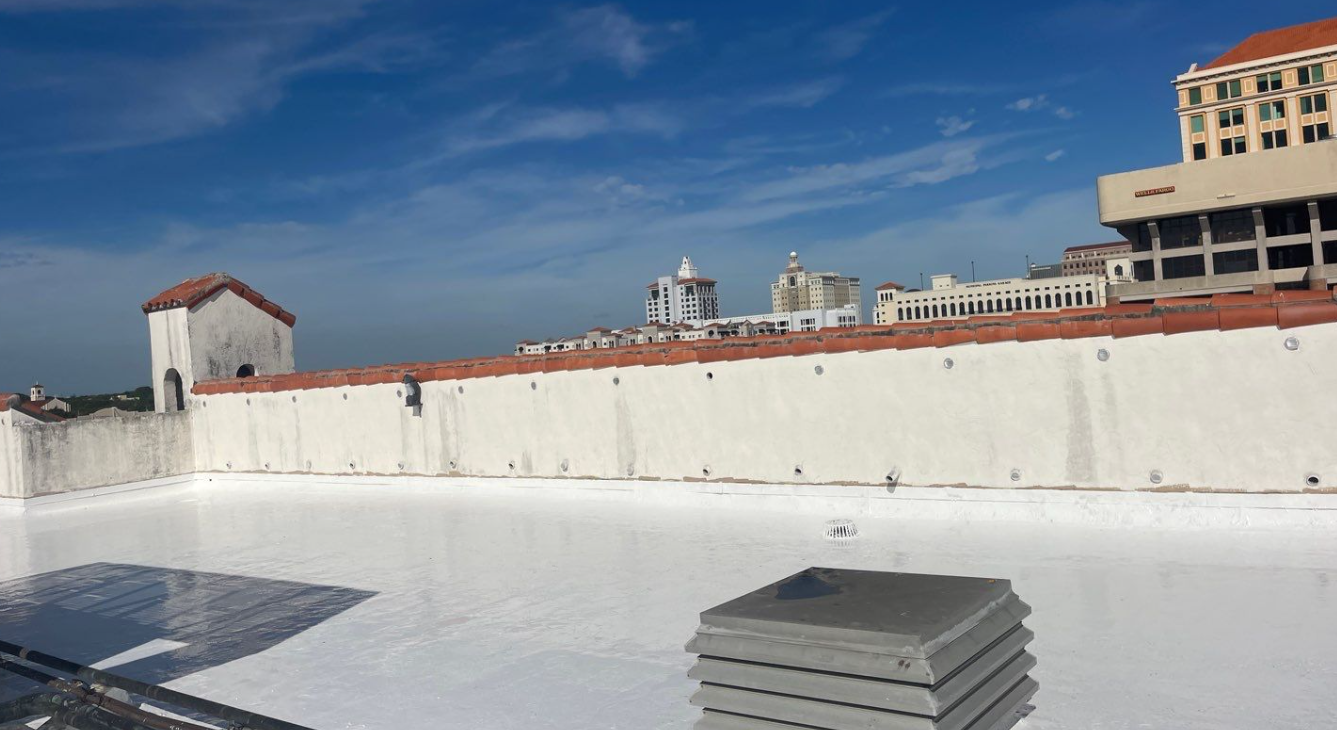 A white roof with a chimney on top of it and a building in the background