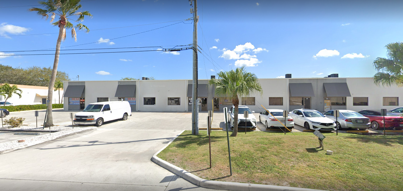 A large white building with a lot of cars parked in front of it