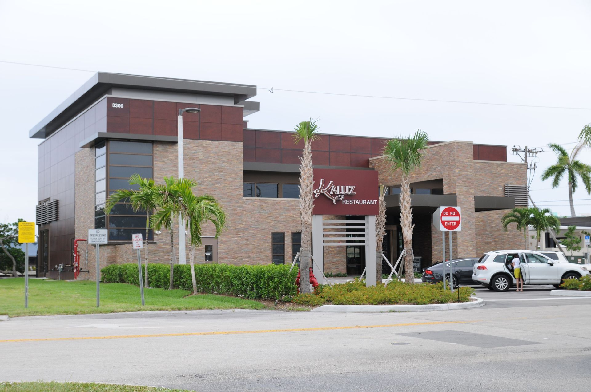 Restaurant building, brick and brown facade, sign R Law Restaurant, palm trees, cars parked.